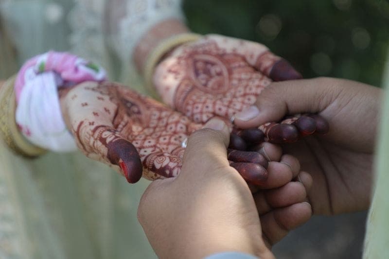 Bridal mehndi being applied to hands at a mehndi ceremony
