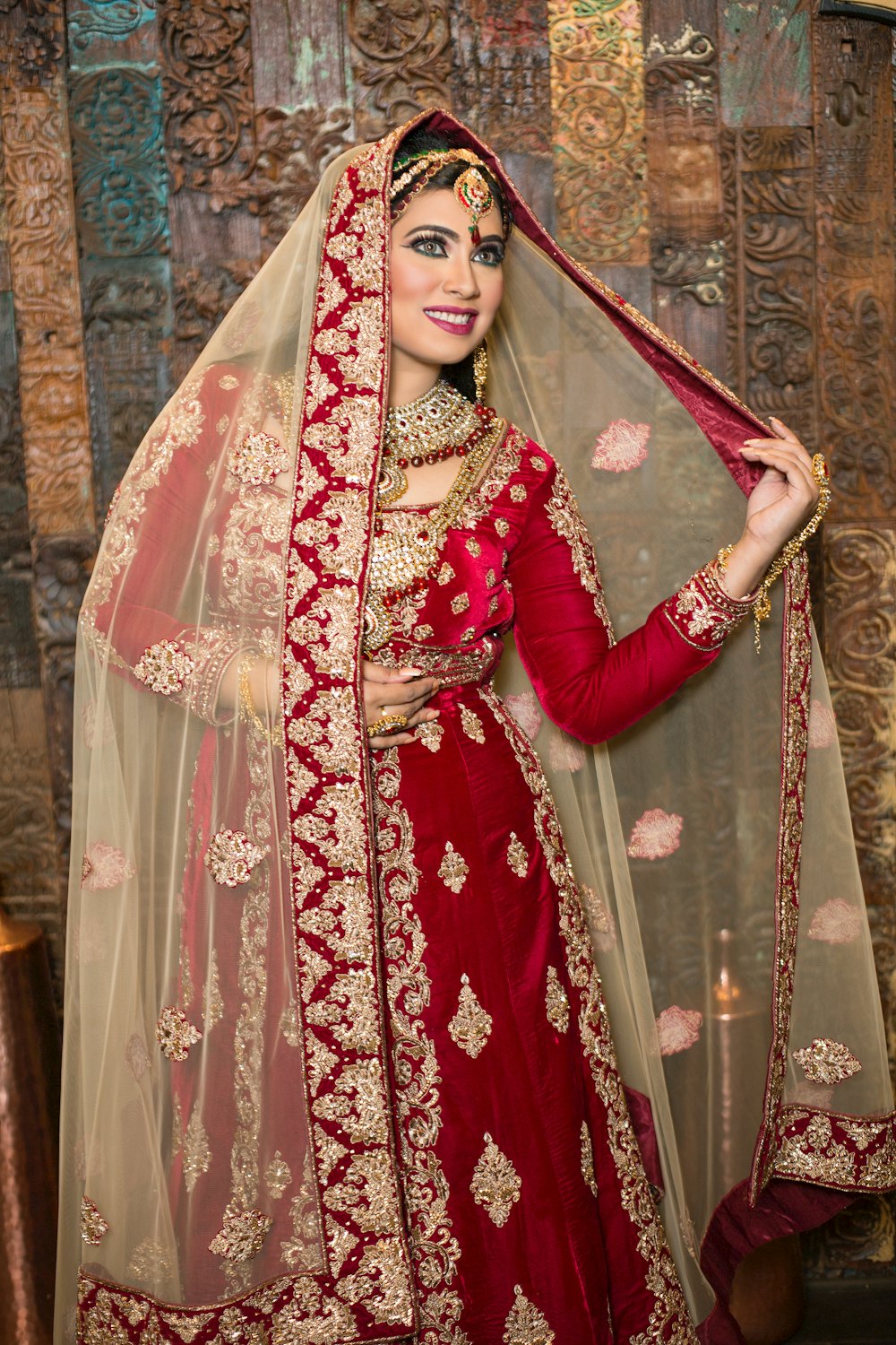 Pakistani bride in a red and gold bridal lehenga with her dupatta drawn overhead